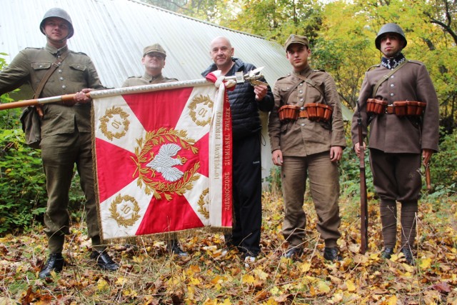 Dziesiątacy z kopią sztandaru przed budynkiem Bolesława Pakuły