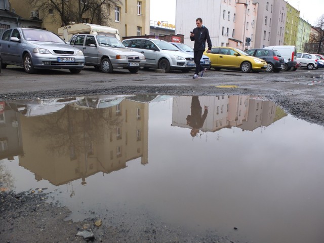 Parkujący na placu między kamienicami przy ul. Ozimskiej mają problemy, aby suchą stopą dojść do samochodów.