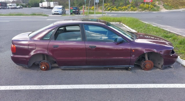 Wrak bez kół znajdujący się na parkingu przy Trasie Północnej.