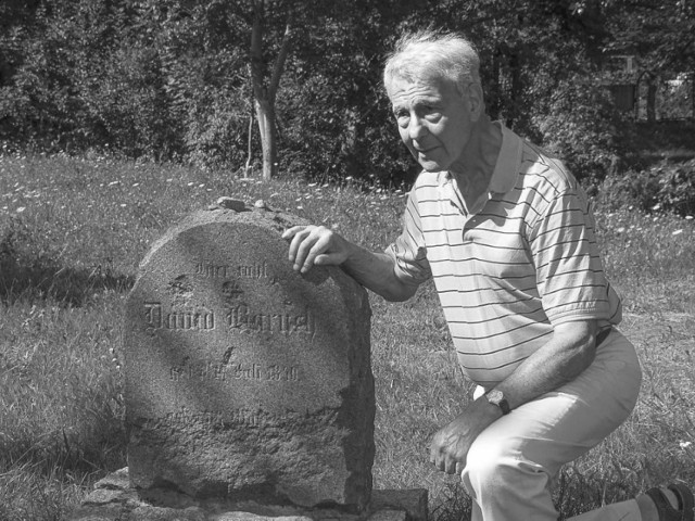 Leslie Brent podczas jednej z wizyt w Koszalinie. Klęczy na terenie cmentarza żydowskiego przy ulicy Rzecznej, przy macewie swojego stryjecznego dziadka, Dawida Barucha.