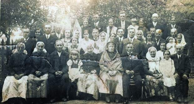 Zdjęcie ze ślubu Jana Otręby z Moniką Szuściel z ok. 1935 r. (państwo młodzi 4. i 5.  z prawej).  Joanna, wtedy  nastolatka, stoi za małą dziewczynką (swoją młodszą siostrą) w środku weselników, między ojcem a matką
