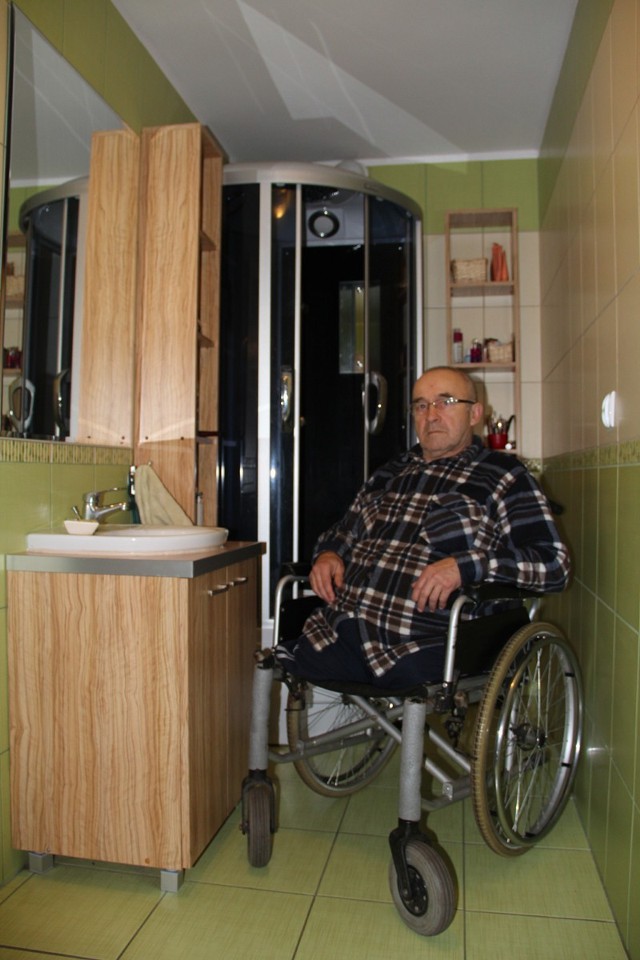 Edward Koćwin w  zaadaptowanej na swoje potrzeby, czyli  osoby niepełnosprawnej, łazience. Za nim kabina prysznicowa