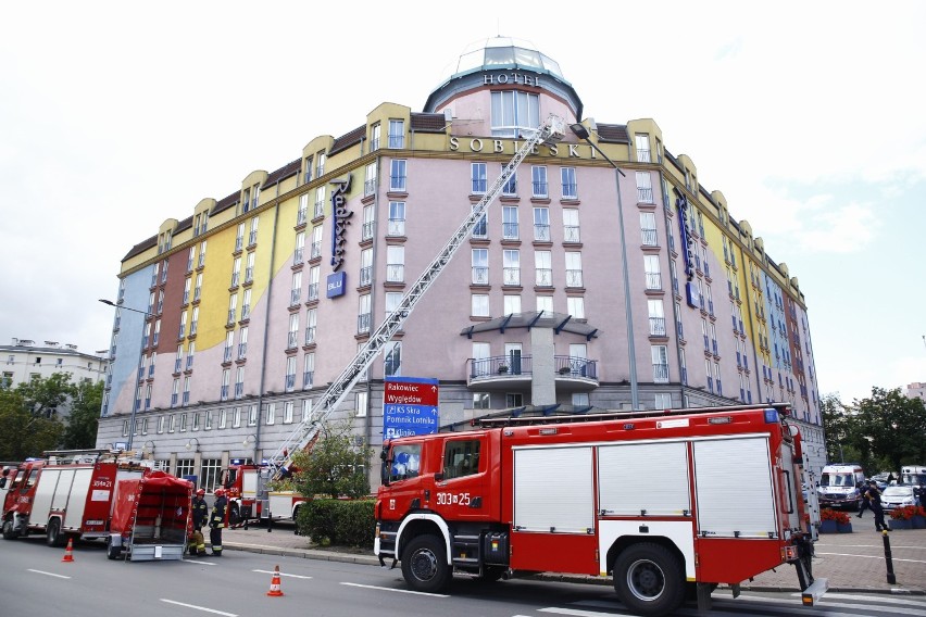 Akcja ratunkowa pod hotelem Radisson Blu Sobieski. Po gzymsie budynku chodzi człowiek 