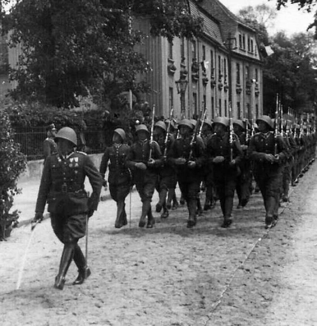 Defilada żołnierzy 56 Pułku Piechoty Wielkopolskiej na ul. Piastowskiej (z tyłu budynek szkoły. Dziś ZSP nr 2) w dniu 3 maja  1936 r.