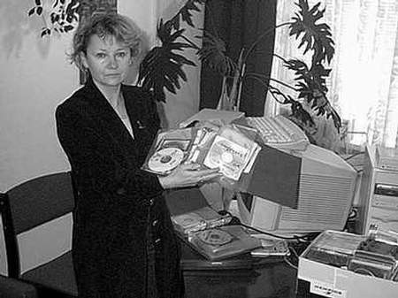 Barbara Buśkiewicz prezentuje część zabezpieczonych płyt. W tle sprzęt komputerowy służący do kopiowania.