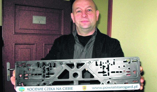 Stefan Galiński z Wydziału Kultury, Sportu, i Promocji Regionu  prezentuje ramkę na tablicę rejestracyjną