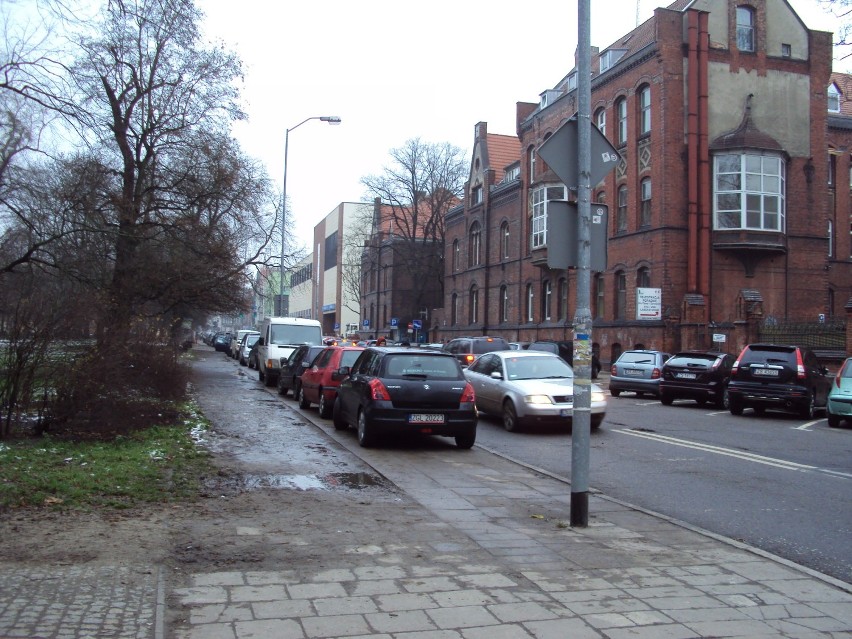 Parkujące na całej szerokosci chodnika przy ul. Wojciecha samochody