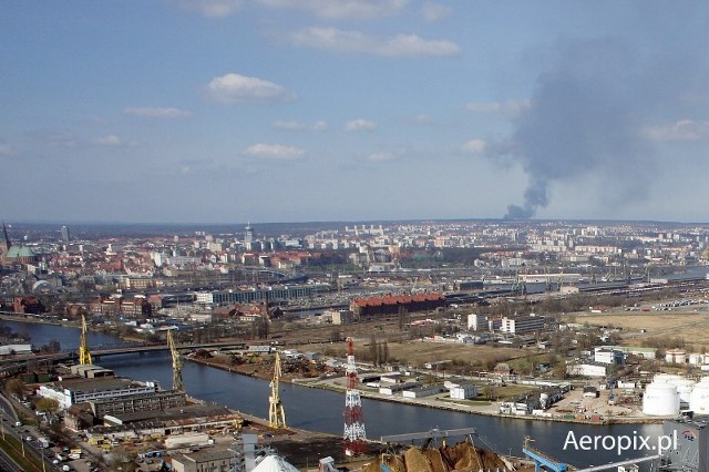 Kadr przedstawia słup dymu widzany z lotu ptaka nad portem w szczecinie  około godziny 15, 26 marca. 

Autor zdjęcia: aeropix.pl