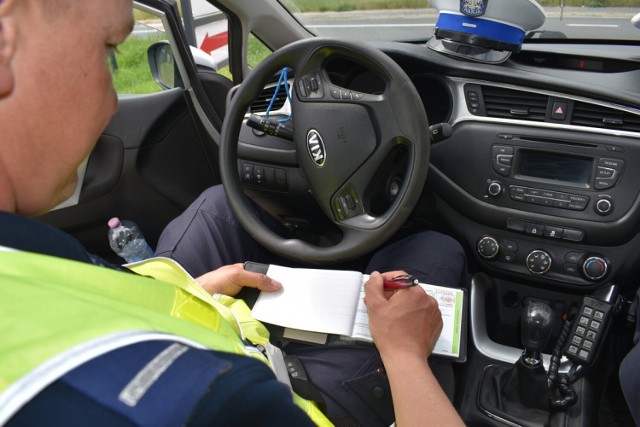Policjant wypisujący mandat za przekroczenie prędkości, podczas akcji "Prędkość" prowadzonej w powiecie obornickim