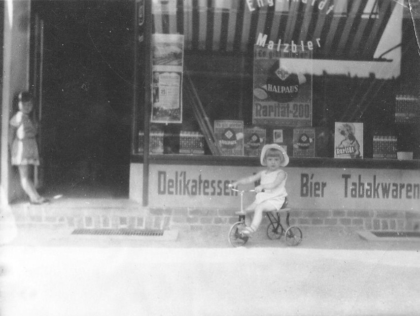 (na zdjęciu: na rowerku mała Ewa 1938 r. przed sklepem ojca...