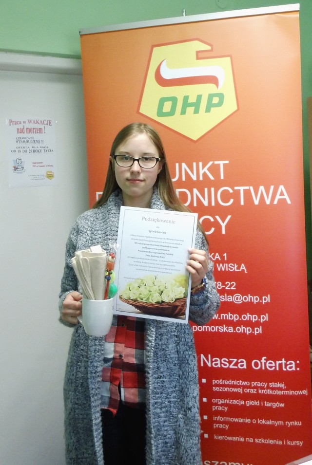 Pani Sylwia Gracek z pamiątkowym dyplomem i gadżetami OHP