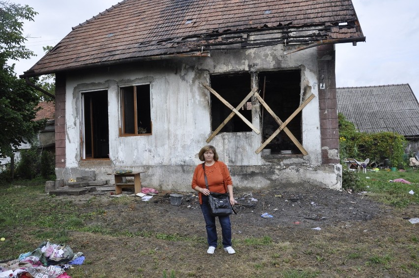 Danuta Ścibor pokazuje zgliszcza spalonego domu. Kobieta...