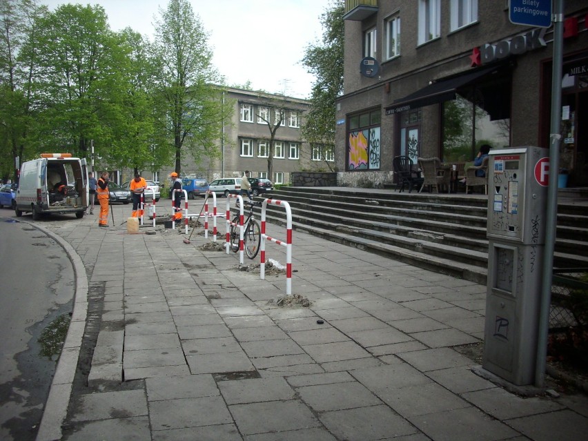 Ekipa drogowa montuje bariery-stojaki rowerowe na szerokim...