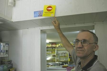Lucjan Szczęsny pokazuje wywieszkę &quot;Zakaz wjazdu niepełnoletnim&quot;, którą powiesił w swoim sklepie nad wejściem do stoiska z alkoholem. Fot. Olgierd Górny