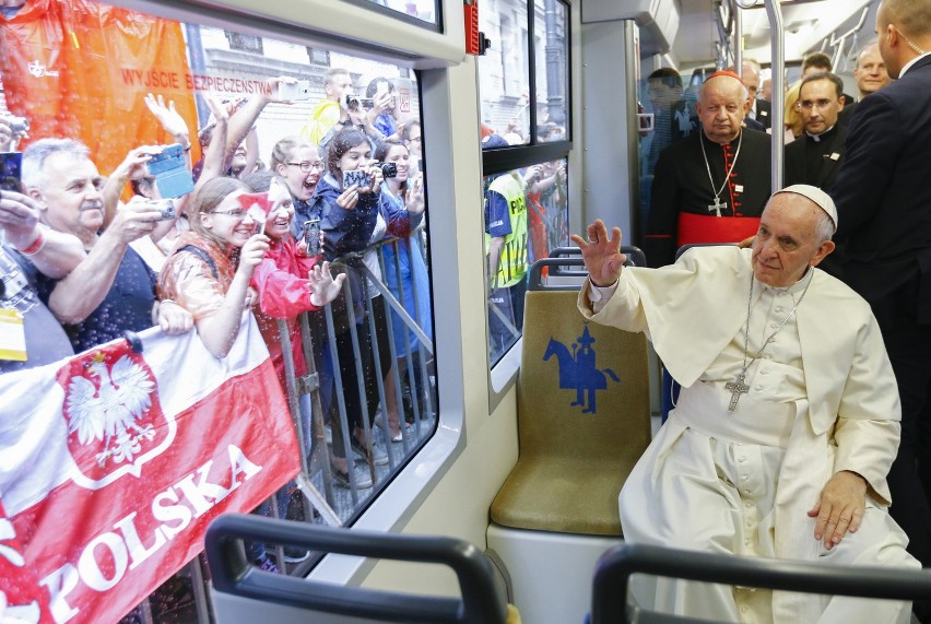 Pope francis waives to a cheering crowd of faithful as he...