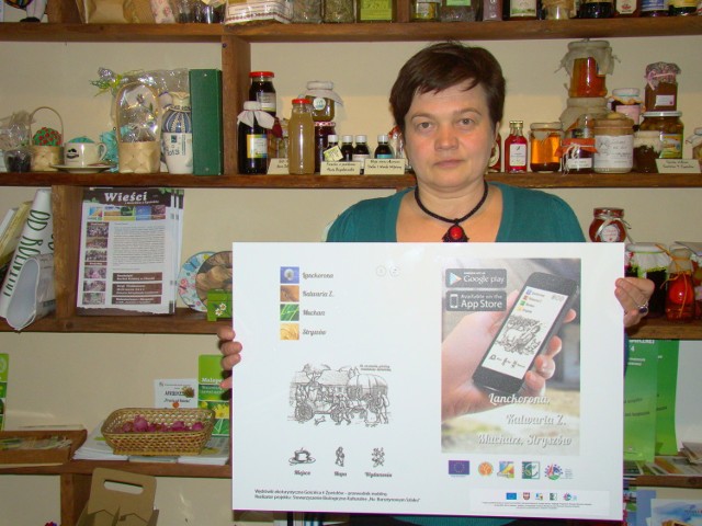 Renata Bukowska, prezes Stowarzyszenia Gościniec 4 Żywiołów, prezentuje planszę z przewodnika mobilnego po gminach.