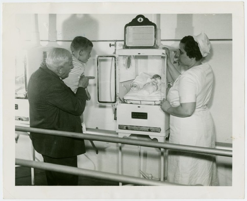 Martin Couney z kobietą patrzą na dziecko w inkubatorze