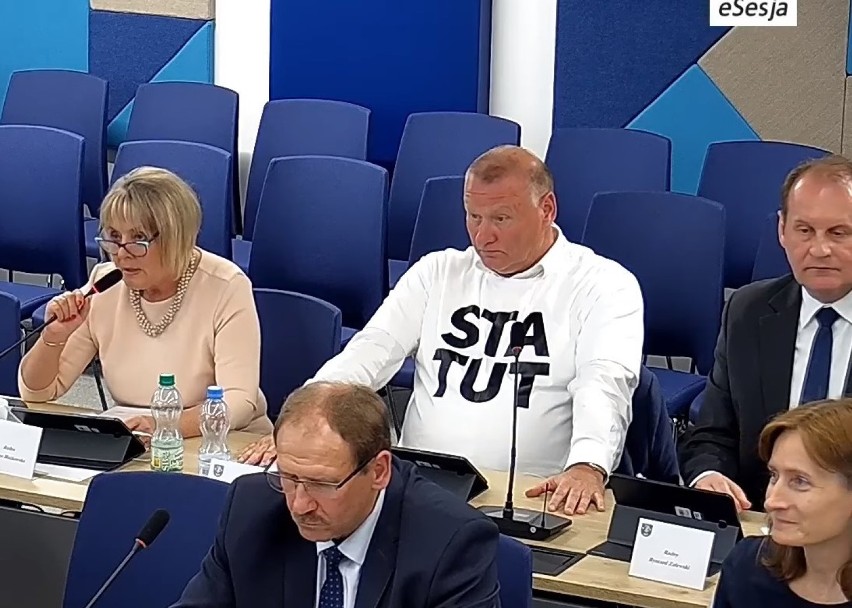 Radny Ireneusz Serwotka w białej koszulce z napisem "statut"...