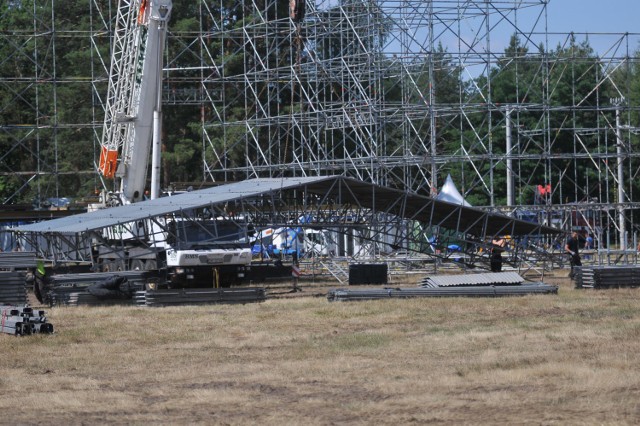 Na festiwalowej łące w Kostrzynie dosłownie w każdym miejscu coś się dzieje. Najbardziej rzuca się w oczy Duża Scena. Główna konstrukcja już stoi, teraz trwa budowa zadaszenia, które ja przykryje.



Teren przed Dużą Sceną przypomina teraz wielki magazyn i plac budowy w jednym. Składowane są tu elementy festiwalowej infrastruktury, rozładowywane są kolejne ciężarówki, a kilkadziesiąt metrów dalej ekipa budowlana uwija się przy budowie Dużej Sceny. Pogoda nareszcie zrobiła się typowo letnia, wyszło słońce i jest ponad 20 stopni. 

Na wzgórzu akademii Sztuk przepięknych widać już ogromny, biały namiot, w którym będą odbywały się koncerty, warsztatu i spotkania. Trwa budowa stoisk gastronomicznych i Pokojowej Wioski Kryszny. Stanął też namiot lidla, rozpoczęła się budowa wioski piwnej. Na polu staje coraz więcej płotów, którymi wygradzane są nimi poszczególne strefy.

Chcesz wiedzieć kto zagra na PolAndRock Festival 2019 (Przystanek Woodstock 2019)? PolAndRock Festiwal 2019 (Woodstock) zespoły, koncerty kto zagra

Polecamy wideo: Z całej Polski pociągiem na Pol'and'Rock Festival. Będzie jednak 70 dodatkowych składów


