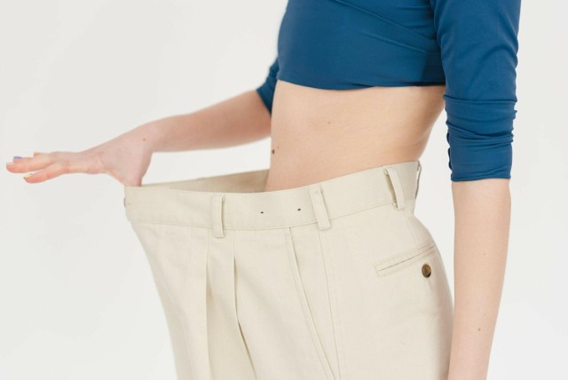Zdrowa waga – kobieta, która schudła, prezentuje za duże spodnie