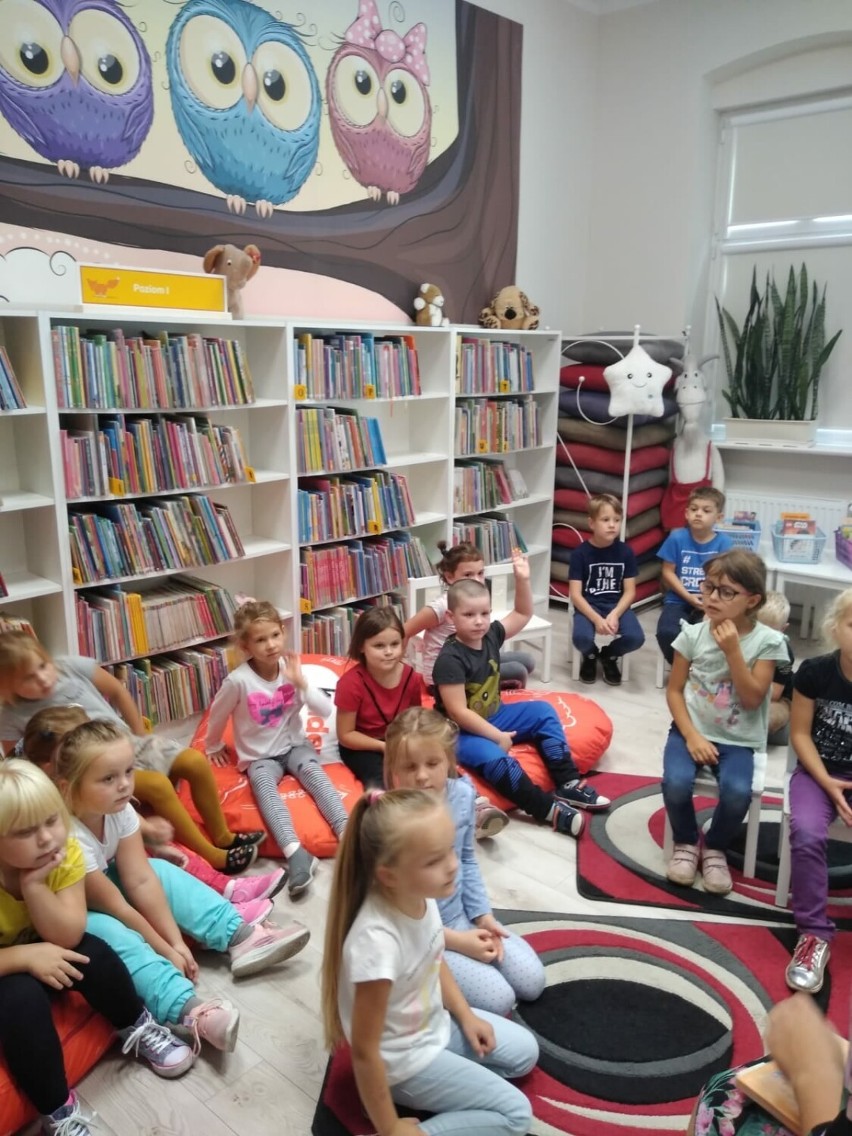 Przedszkolaki wśród regałów z książkami. Pierwsze wizyty w bibliotece.