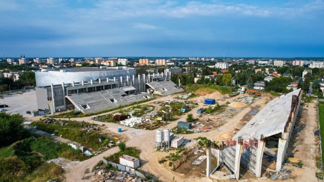 Kiedy powstanie stadion radomskiego Centrum Sportu, na którym mają grać piłkarze Radomiaka? Na to pytanie wszyscy chcielibyśmy znać odpowiedź. Termin oddania mija z końcem 2021 roku, ale już wiadomo, że będzie on przesunięty. Niewiele się dzieje na obiekcie, choć trwają prace przy trybunie północnej. Jak już pisaliśmy, na tej trybunie trwa montaż ścianek szczelnych wokół zbiornika retencyjnego. To są konieczne prace, zanim rozpocznie się naprawa samego zbiornika. Dopiero po zakończeniu prac ze zbiornikiem dokończone zostanie wzmacnianie gruntu pod fundamentami trybuny północnej i wówczas zmontowana zostanie ona do końca. Praktycznie to samo trzeba zrobić z trybuną południową.
Otrzymaliśmy garść znakomitych fotografii zrobiony z lotu ptaka. Autorem zdjęć jest twórca profilu facebookowego Radomski Dron. Zachęcamy do oglądania 
ZOBACZ KOLEJNE ZDJĘCIA ===>>>