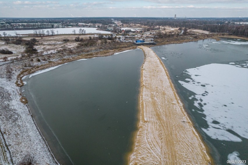 Nad stawem, drogą powiatową i torami pobiegnie prawie...