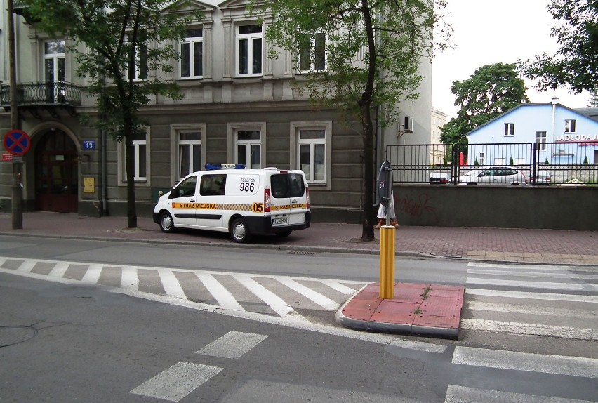Samochód straży miejskiej zaparkowany przy przejściu dla pieszych.