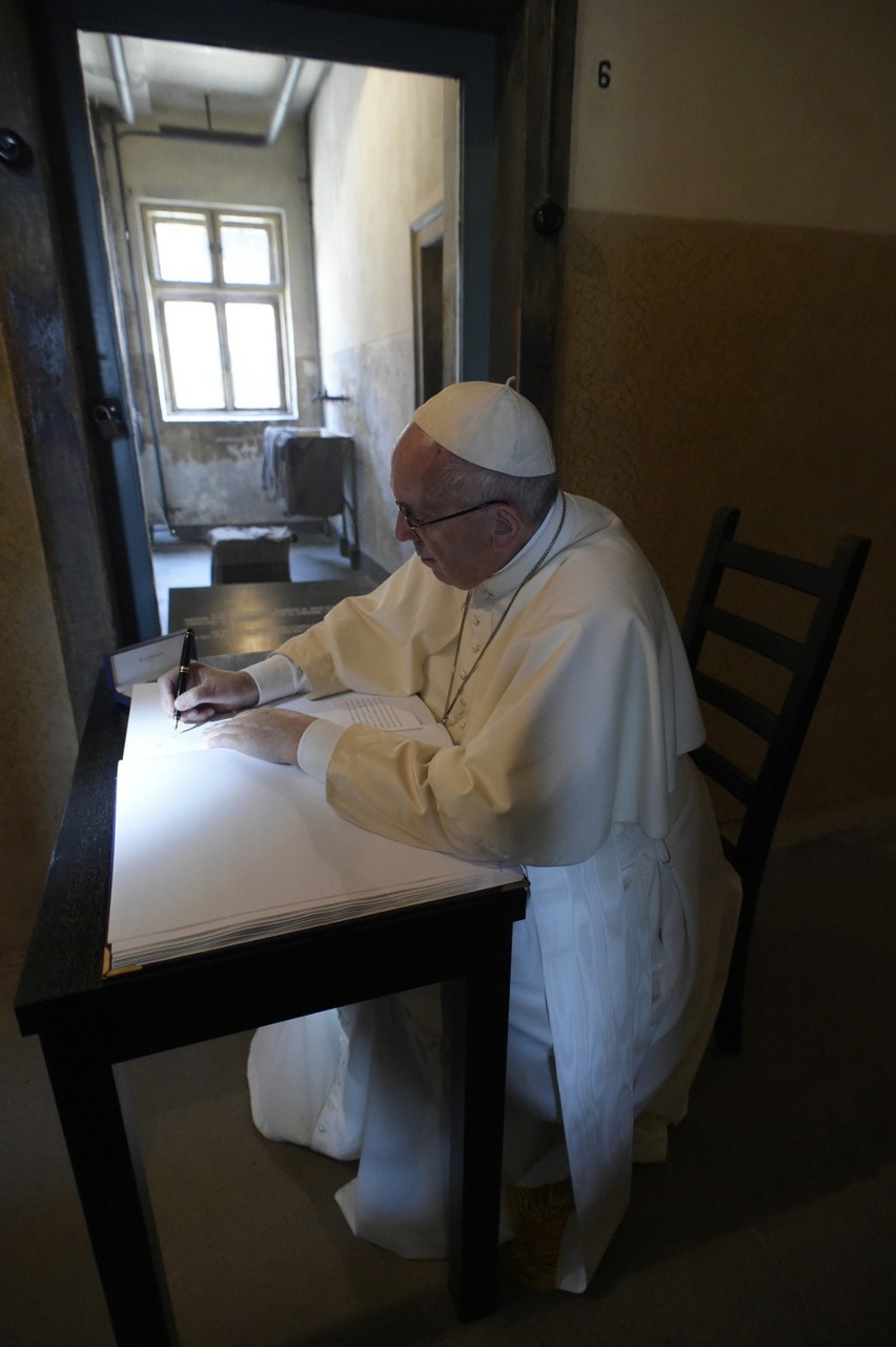 Pope francis writes on the guest book at the end of his...