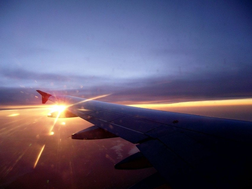 Z maleńkiego okienka samolotu, wschodzące słońce.