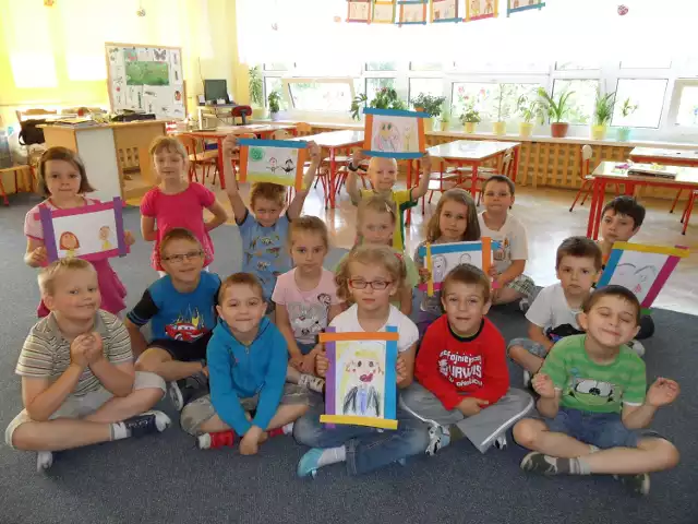 Dzieci z Przedszkola nr 5 w Żorach pokazują rysunki, na których prezentują swoje kochane mamy