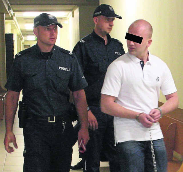 Oskarżony Dawid B. doprowadzany w konwoju policyjnym na rozprawę przed  krakowskim sądem w sprawie krwawej bójki