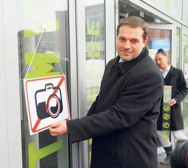 Sławomir Murawski, dyrektor Manufaktury, zamienia znak zakazu fotografowania na znak aparatu z uśmiechniętym obiektywem.