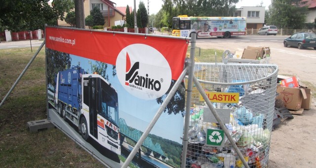 Pojemniki ze śmieciami od ulicy Witoszyńskiej oddzielają panele z logo spółki „Saniko”