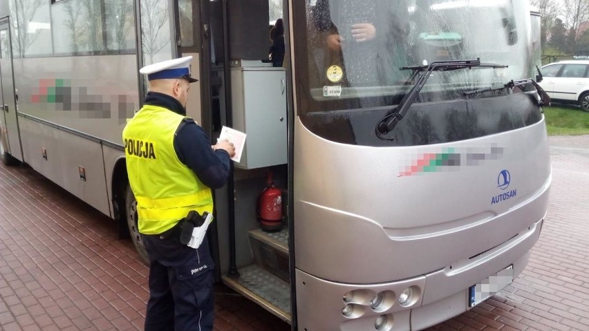 Policjanci kontrolują autokary przed wyjazdem.