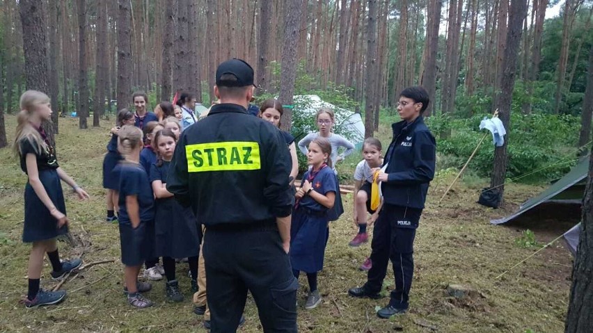 Policjanci i strażacy z wizytami w lesie. Odwiedzają obozy harcerskie 