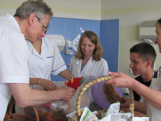 Dr Piotr Suda wraz z pracownikami szkoły szpitalnej wręcza upominki małym pacjentom kaliskiej lecznicy.