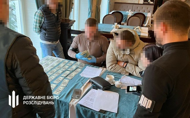 Ukraiński celnik (nz. w jasnej kurtce, drugi z prawej)jest podejrzany o przyjmowanie ogromnych łapówek za "zamieniania" w dokumentach komercyjnych ładunków na "pomoc humanitarną".