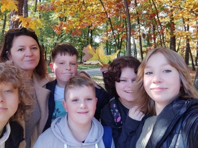 Uczniowie z polonistką na lekcji w jesiennym parku