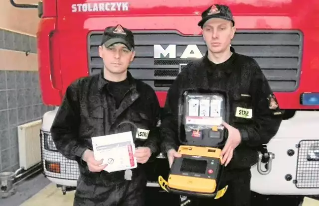 Mł.ogn.  Piotr Orlof i st. str. Tomasz Szczerba z defibrylatorem  typu AED, którego użyli podczas akcji