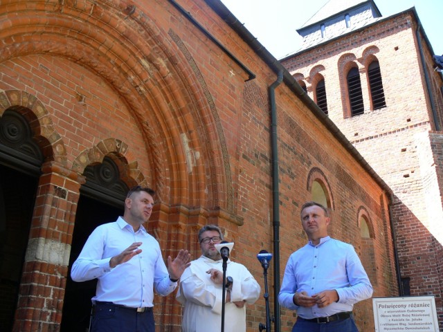 Od lewej na tle kościoła i zabytkowej dzwonnicy, gdzie znajdują się odnowione dzwony : burmistrz Marcin marzec, przeor klasztoru Dominikanów o. Marcin Lisak i starosta Marcin Piwnik.