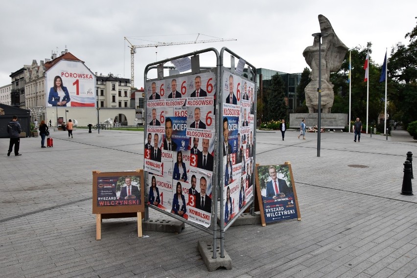 Kandydaci PiS zaklejają się nawzajem na stojaku na ul....