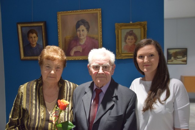 Czesław Ślosarczyk z żoną Krystyną i wnuczką Anną Sitko na tle portretów żony, wnuczki i nieobecnego na wystawie wnuka