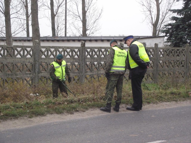 Policjanci przeszukują miejsce w którym znaleźli samochód bandytów