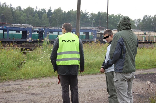 Jeden z zatrzymanych złodziei z policjantami podczas wizji lokalnej w rejonie dworca w Miasteczku Śląskim