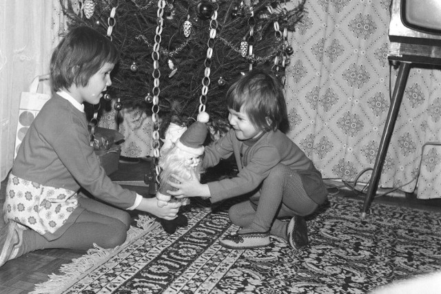 Boże Narodzenie ma swój niepowtarzalny urok m.in. za sprawą świątecznych prezentów. Na zdjęciu: dzieci Zofii Zielińskiej podczas świąt Bożego Narodzenia trzymają w rękach maskotkę św. Mikołaja pod choinką. Z prawej strony widać telewizor Neptun 312. (1975 rok)