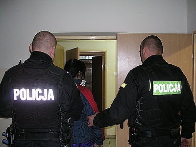 Policjanci prowadzą za kraty zatrzymaną matką dwulatki.