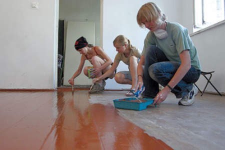 Paulina Łubiarz, Wiktoria Woińska i Gosia Kucińska malują podłogę w ośrodku.