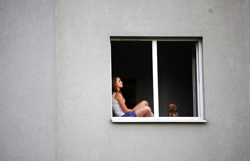 Dziewczyna w oknie z psem podczas zawodów żużlowych Wandy...