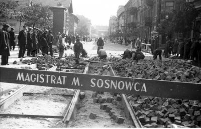 Układanie bruku na jezdni i torowisku. Widoczni przechodnie, obserwujący pracę robotników. Rok 1933. Sosnowiec.